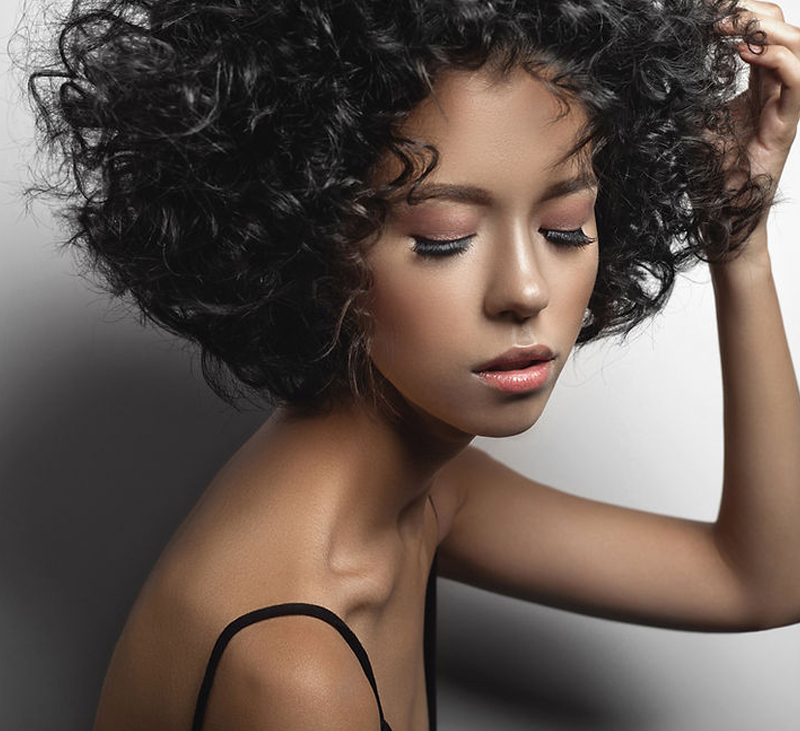 A woman with curly textured hair looking down towards the floor