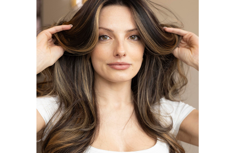 A woman with long wavy carmel highlighted hair