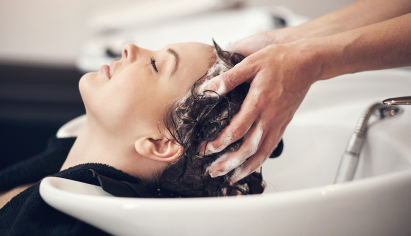 Woman at hairdressing basin having her hair washed
