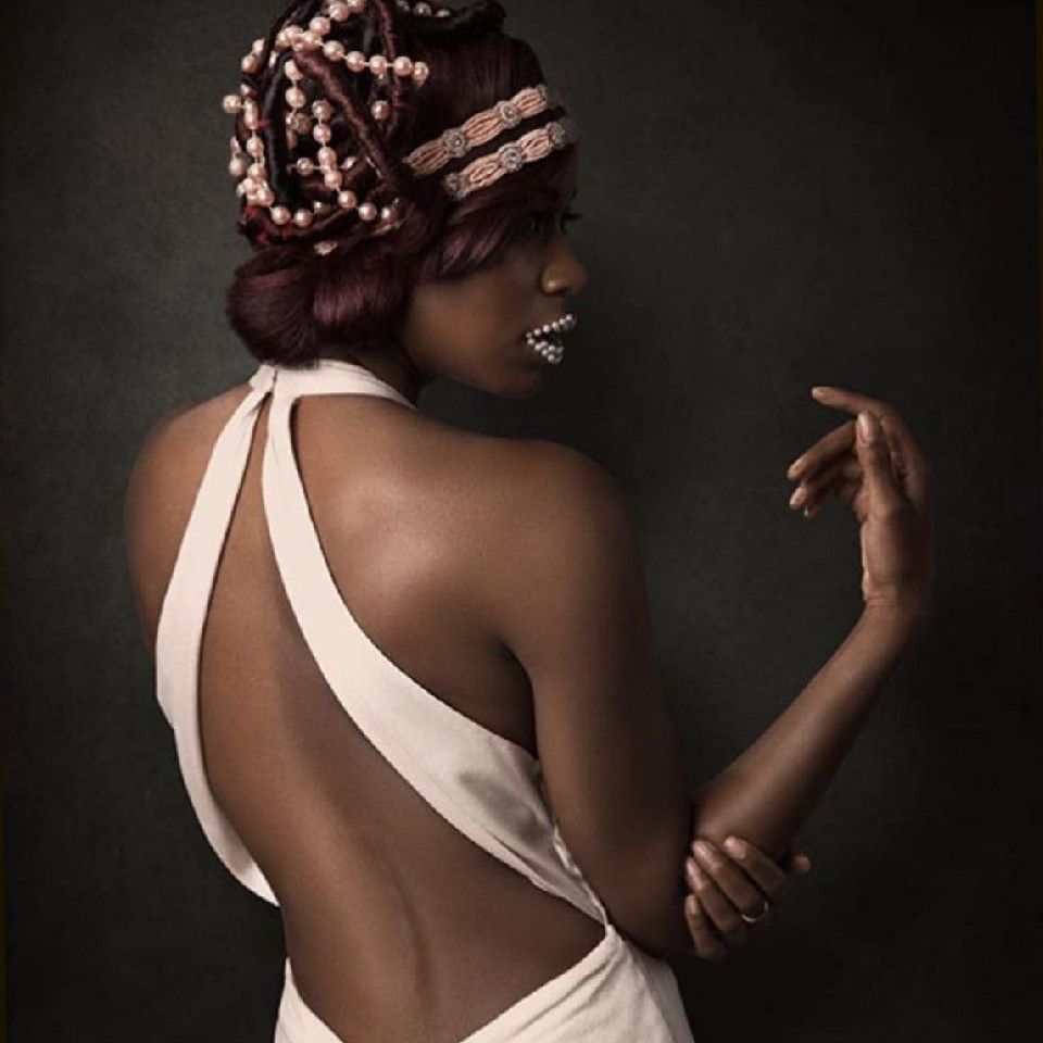 A model with hair-up and beads threaded through hair and on lips