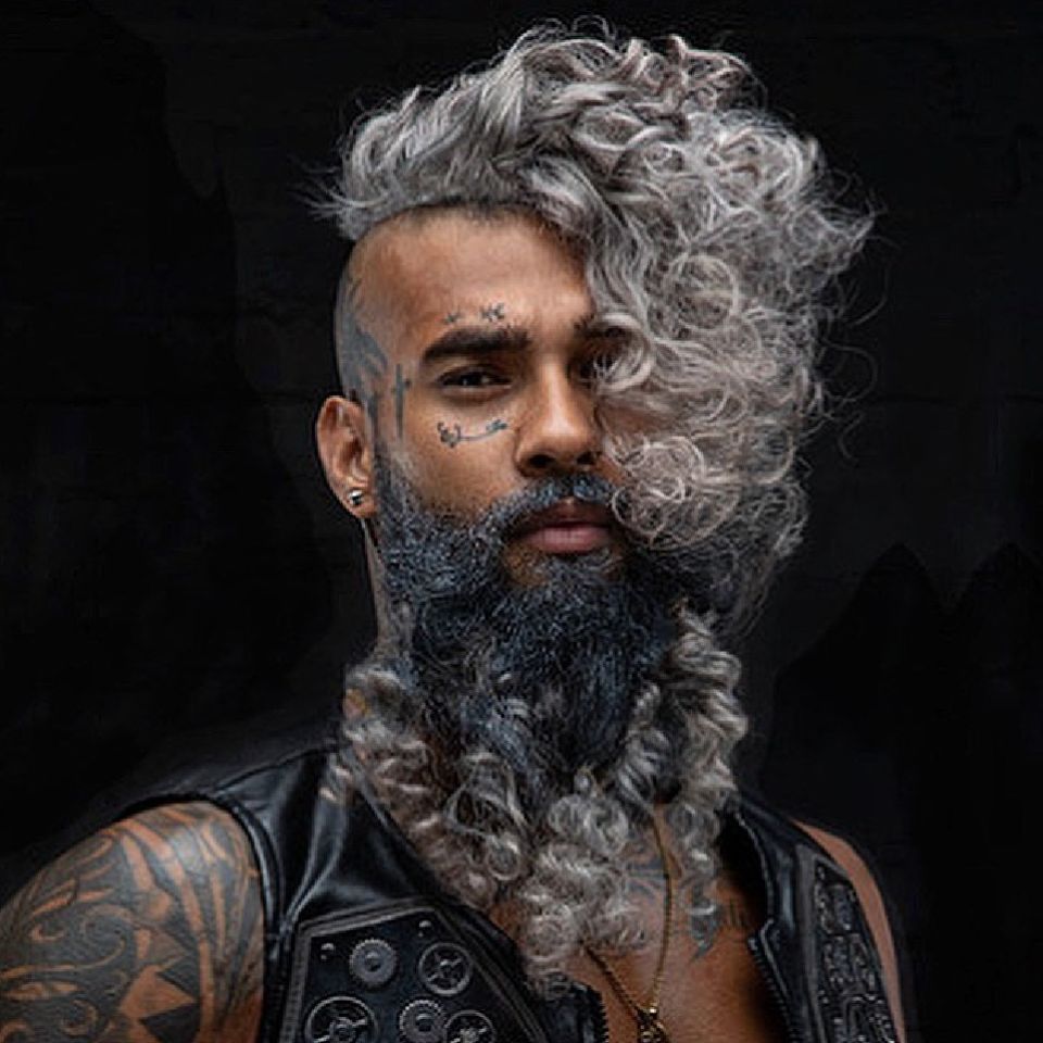A male model with permed grey hair to one side and a permed grey beard