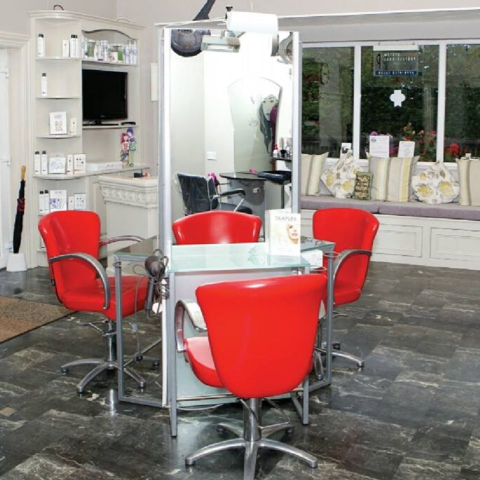 An image of three red chairs at sling stations in the centre of the salon