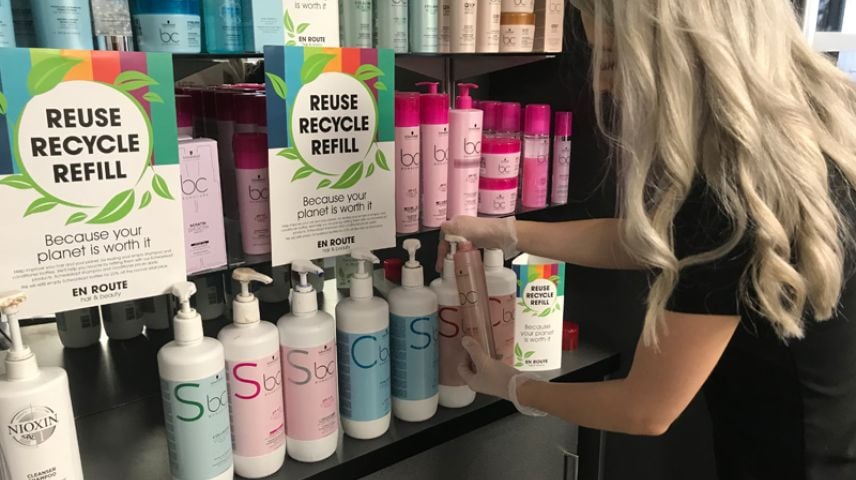 A woman stood at a hair salon retail display looking at a bottle of shampoo