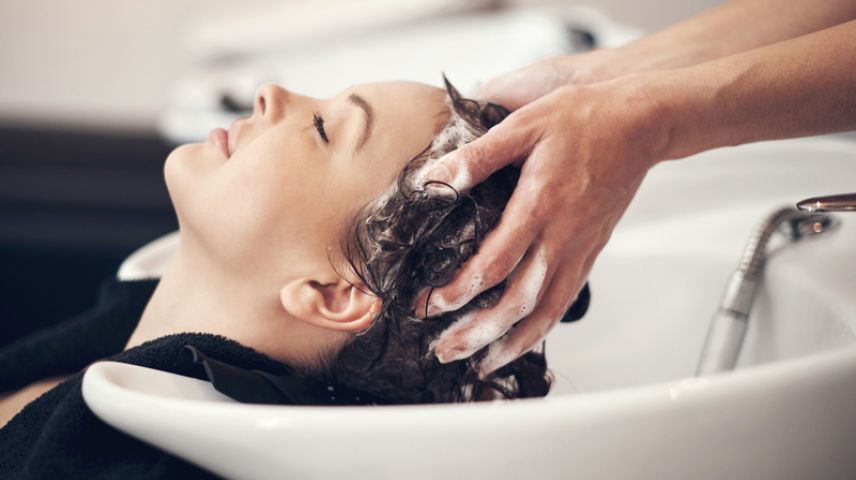 Woman at hairdressing basin having her hair washed