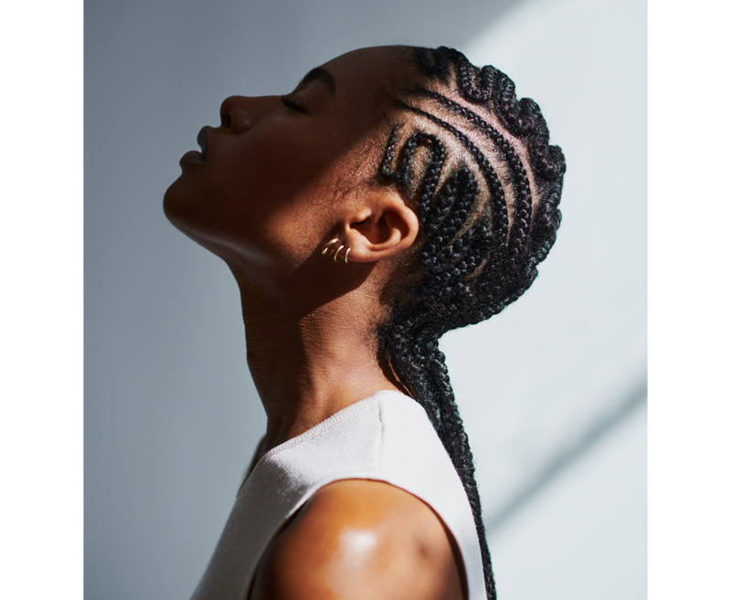 A woman with cornrows with her head tilted back looking upwards