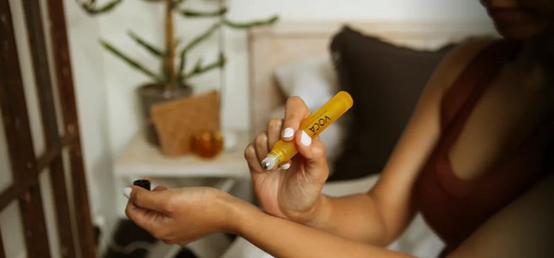 A woman applying VOCA London's rollerball to her wrist 